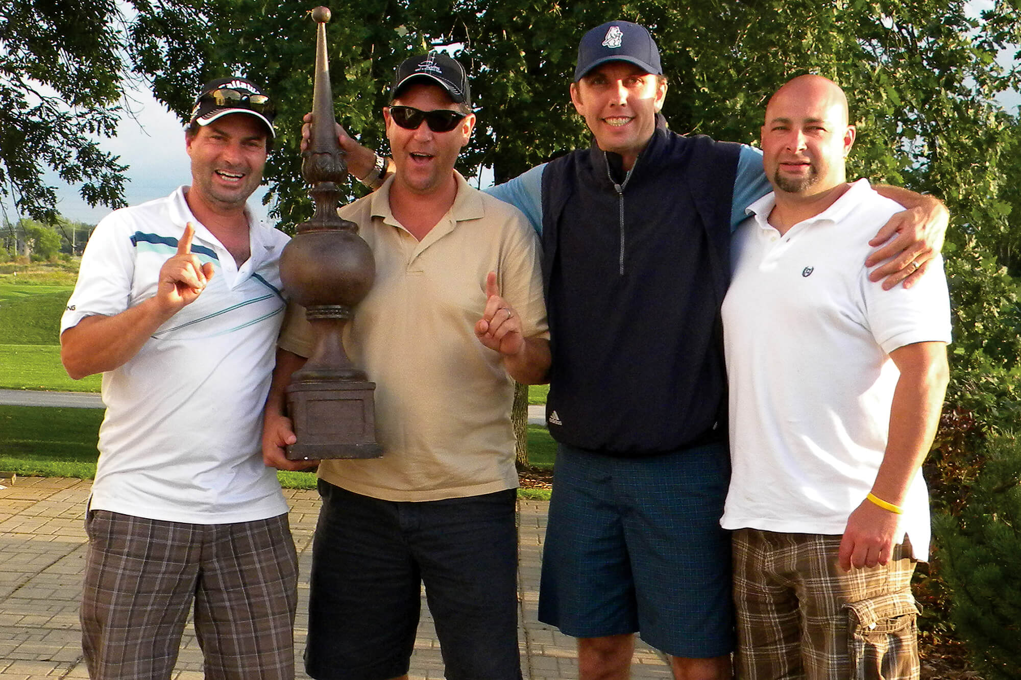 four men posing with a large trophy